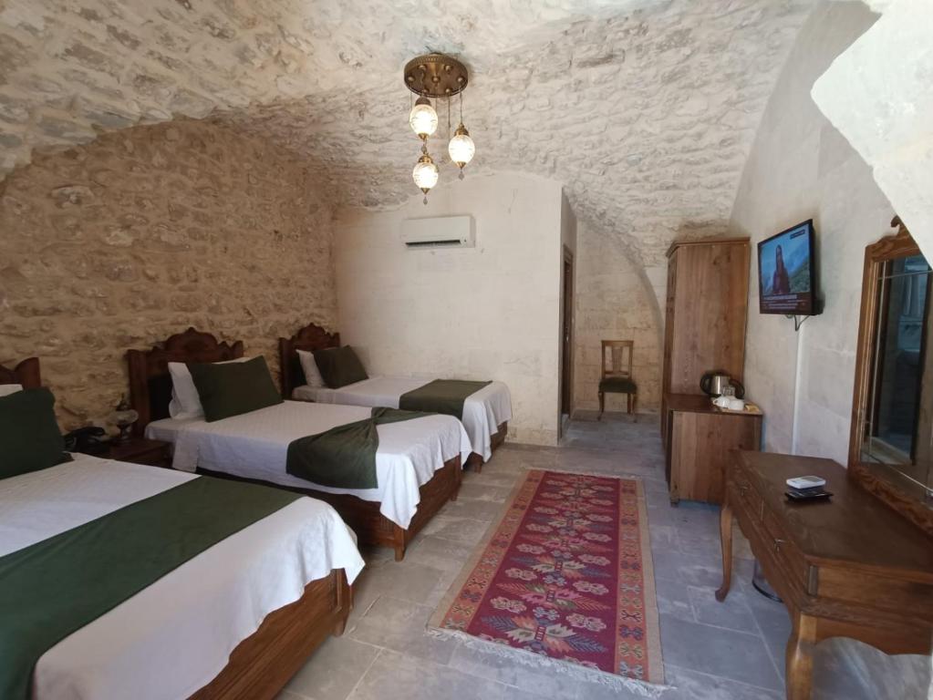 una camera con 4 letti in una stanza con parete in pietra di Fırfırlı Konak a Şanlıurfa