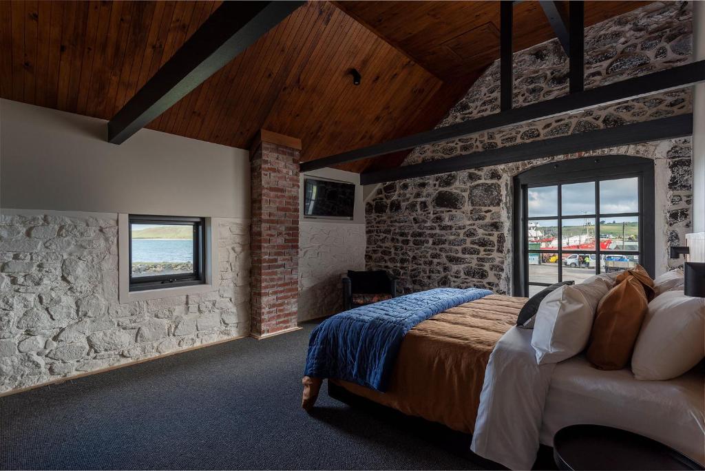 a bedroom with a bed and a stone wall at Bond Store Stanley in Stanley