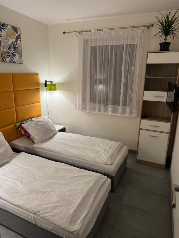 two beds in a small room with a window at Apartament Nad Nielbą in Wągrowiec