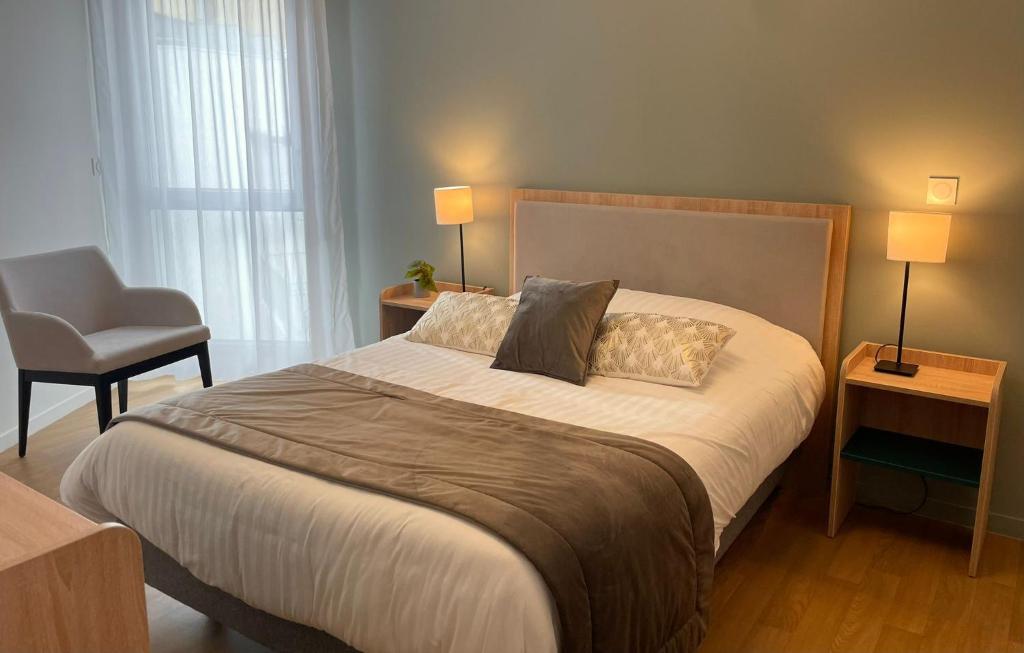 a bedroom with a bed with two pillows and a chair at Zenao Appart'hôtels Dijon in Dijon