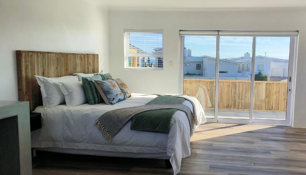 Un dormitorio con una cama y una puerta corrediza de vidrio. en Audrey Hepburn Suite Yzerfontein, en Yzerfontein