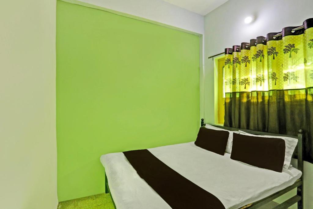 a bedroom with a green wall and a bed at SPOT ON 7 Day Stay in Chandrapur