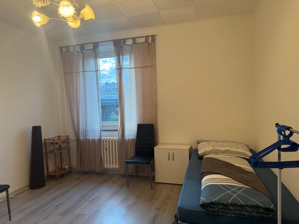 a bedroom with a bed and a window and a chair at K&K Unterkunft Gelsenkirchen in Gelsenkirchen