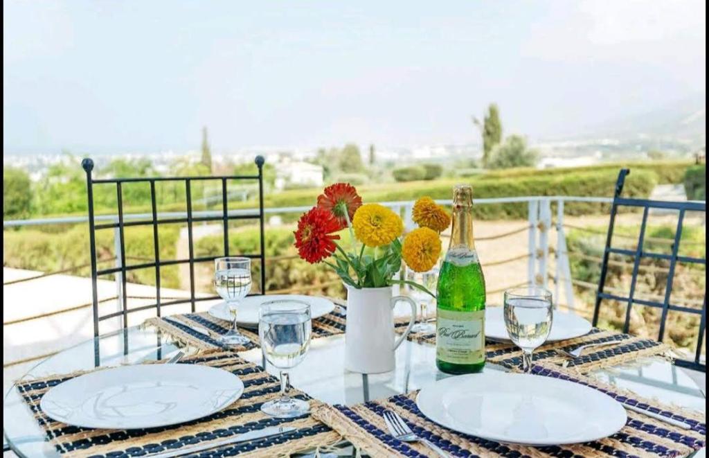a table with plates and a bottle of wine and flowers at Amazing Sea View -3 Bed Ground Floor Garden Apartment in Kérynia