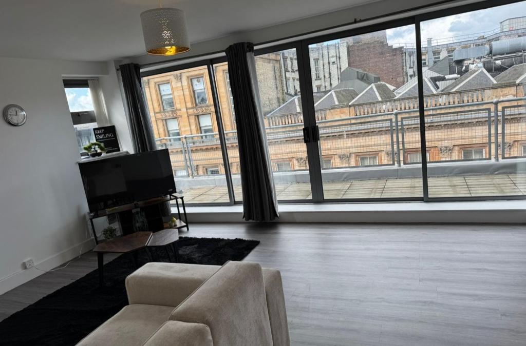 Una sala de estar con un sofá y una ventana grande. en Buchanan Penthouse, en Glasgow