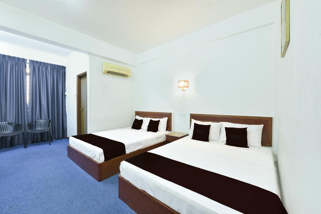 a hotel room with two beds and a window at Hotel Jalan Bukit Ubi Formerly Bumimas in Kuantan