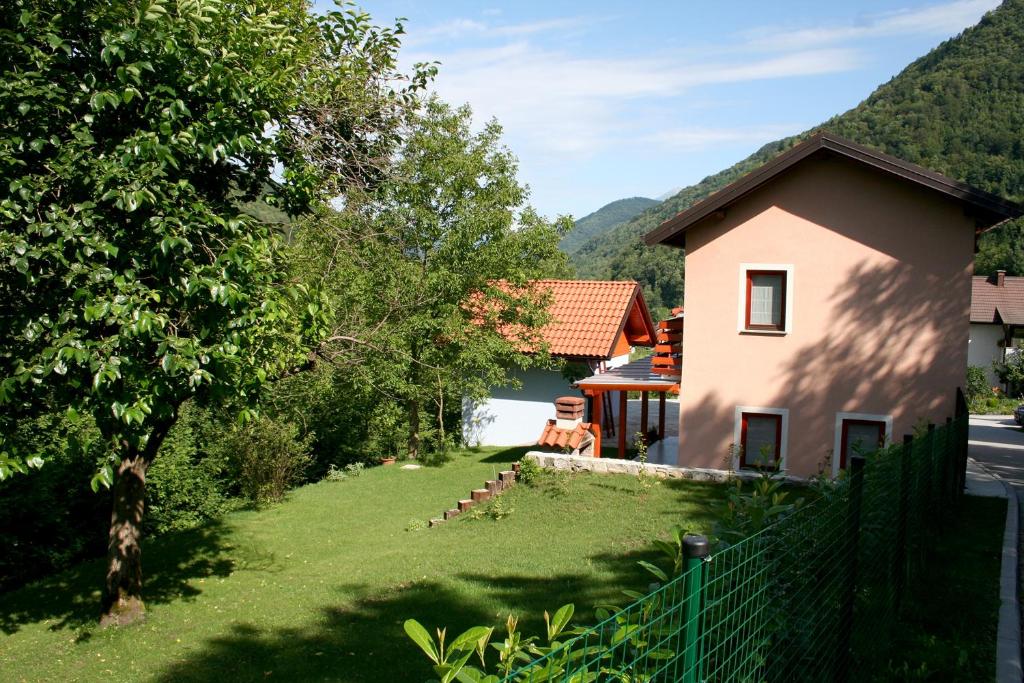 a house with a fence in front of a yard at Bed & Fishing House in Slap ob Idrijci