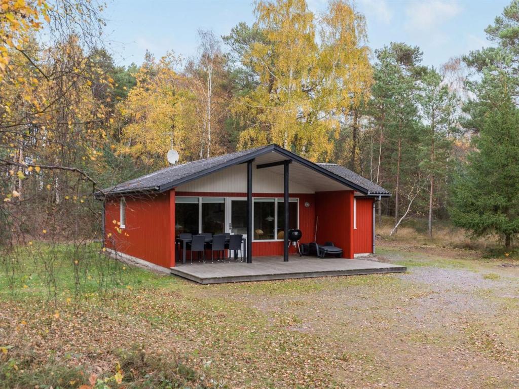 a red cabin with a deck in the woods at Holiday Home Gerty - 300m from the sea by Interhome in Vester Sømarken