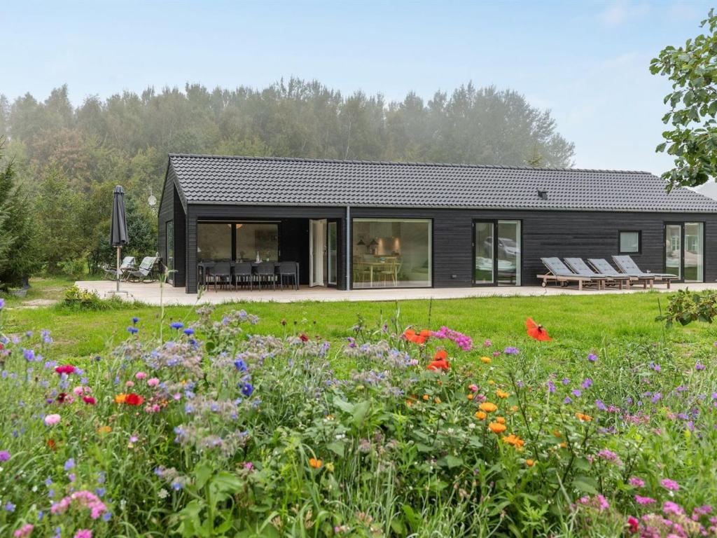une maison noire avec un jardin fleuri dans l'établissement Holiday Home Iivo - 350m from the sea by Interhome, à Vester Sømarken