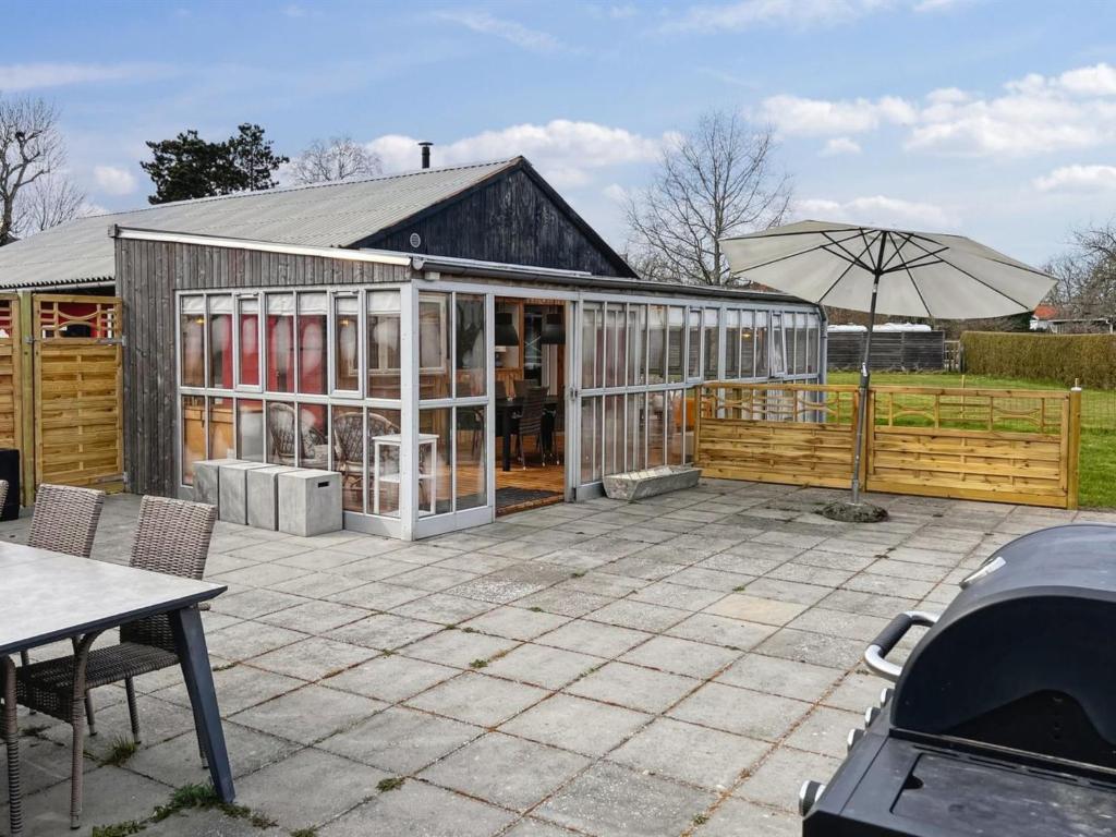 Un invernadero con una sombrilla en un patio. en Apartment Erblin - 250m from the sea by Interhome, en Neksø
