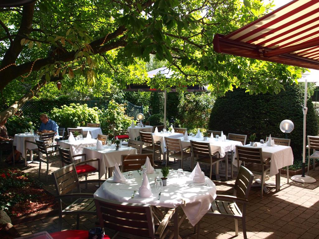 タンにあるHotel Restaurant Aux Sapinsの木の下に白いテーブルと椅子があるレストラン