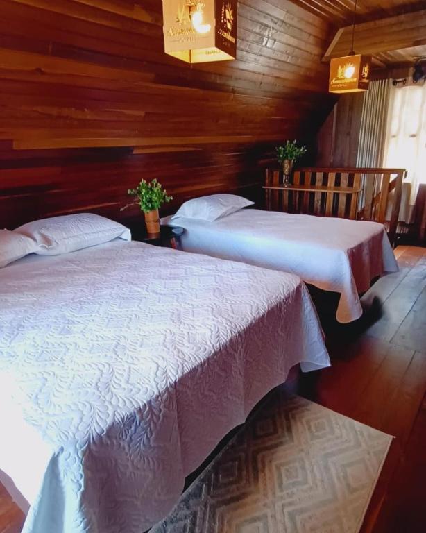 two beds in a room with wooden walls at Sonnenblumen chalet in Mafra