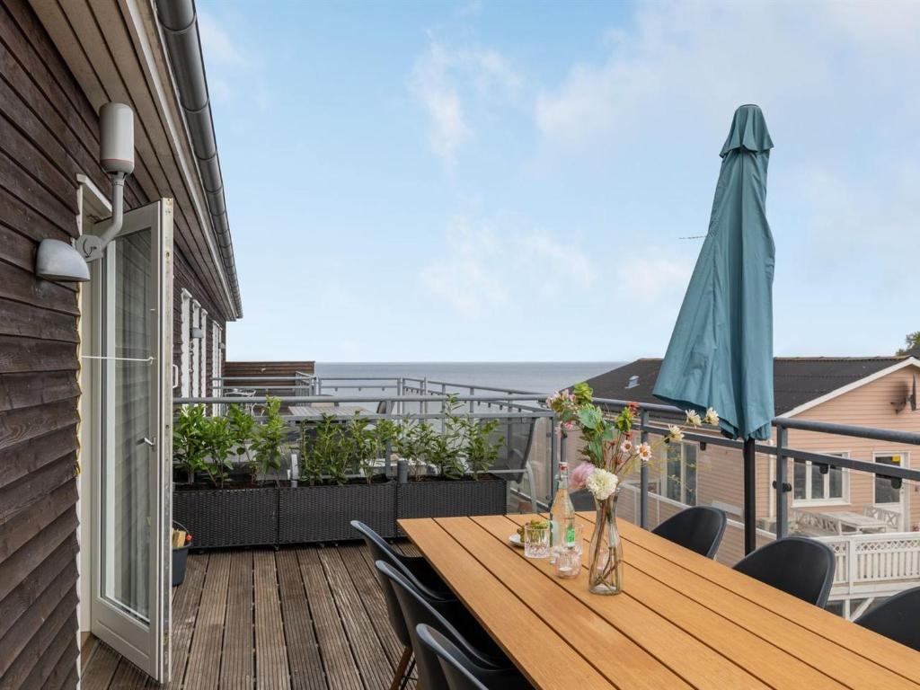 a balcony with a wooden table with chairs and an umbrella at Apartment Hermann - 100m from the sea by Interhome in Allinge