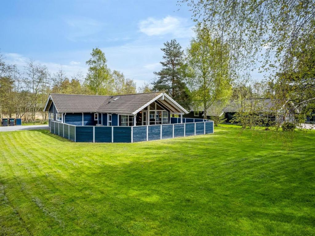 a blue house on a grassy field with a building at Holiday Home Alger - 800m from the sea by Interhome in Marielyst