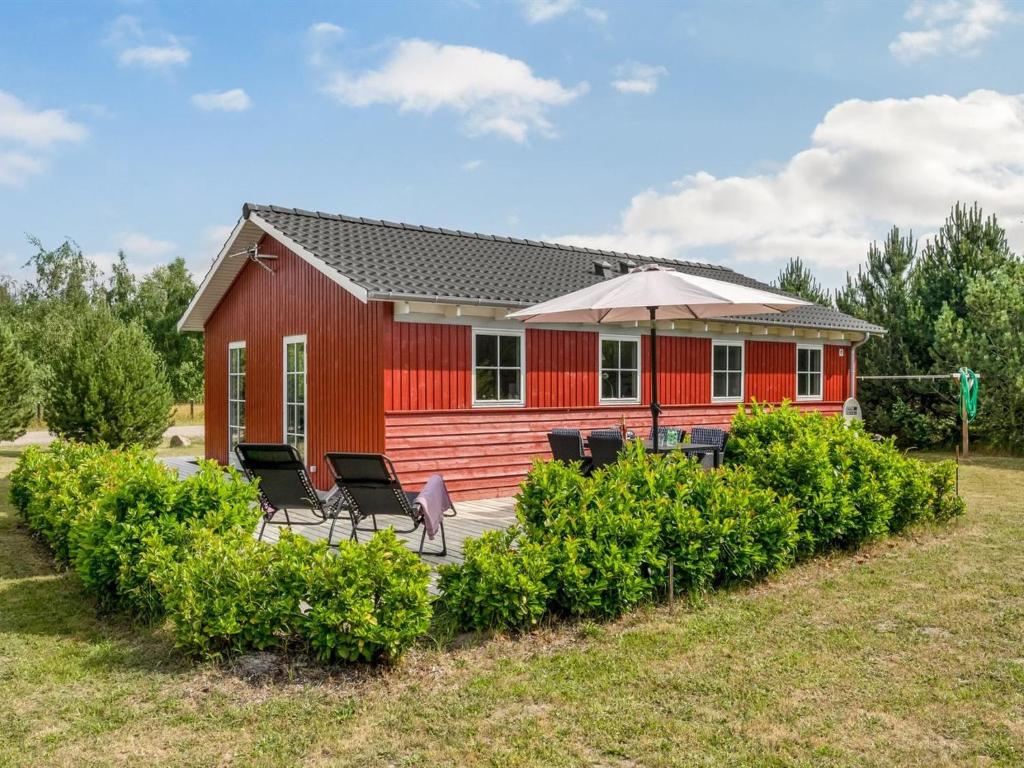 a red house with chairs and an umbrella at Holiday Home Finwith - 1-5km from the sea by Interhome in Marielyst