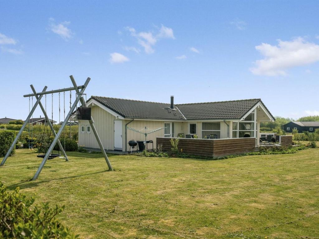 a yard with a swing in front of a house at Holiday Home Reimer - 700m from the sea by Interhome in Neder Lysabild