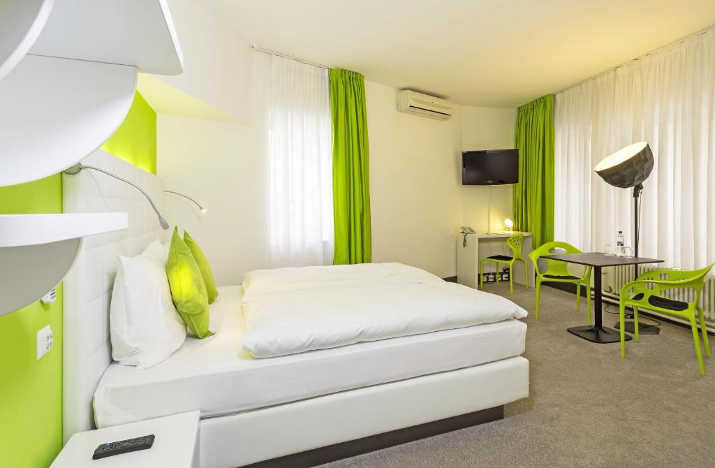 Hotel City Inn Basel في بازل: غرفة فندقية بسرير وطاولة وكراسي