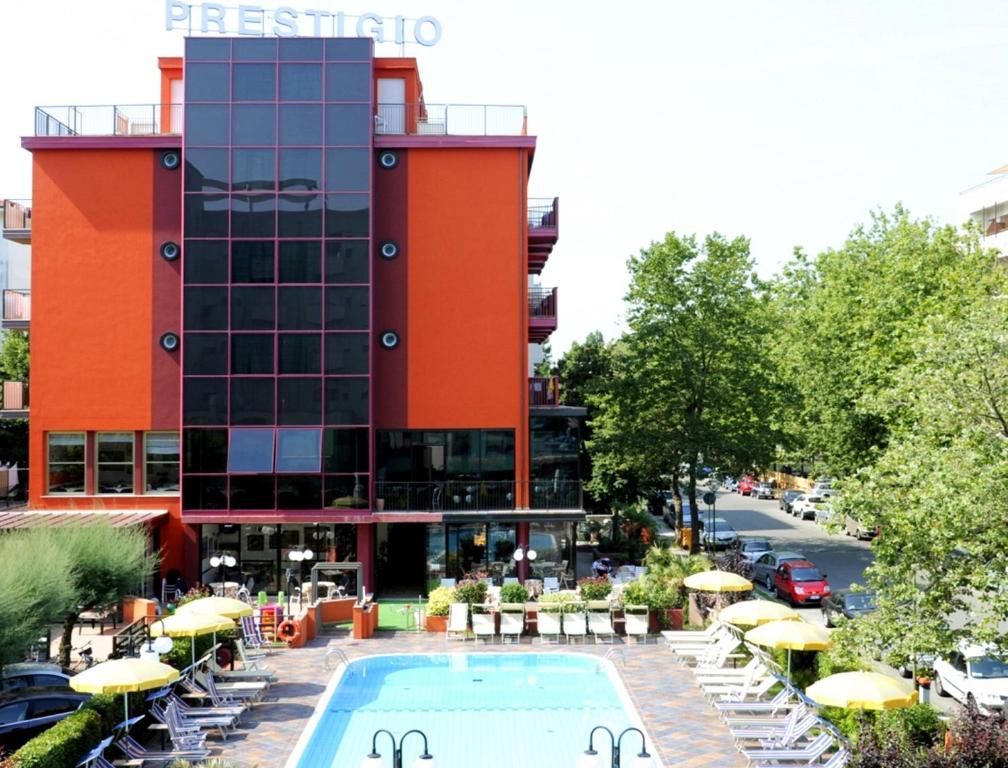 an outdoor swimming pool in front of a building at Hotel Prestigio in Cesenatico