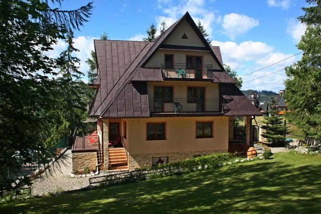 a house with a gambrel roof on a yard at Willa Pasja in Zakopane