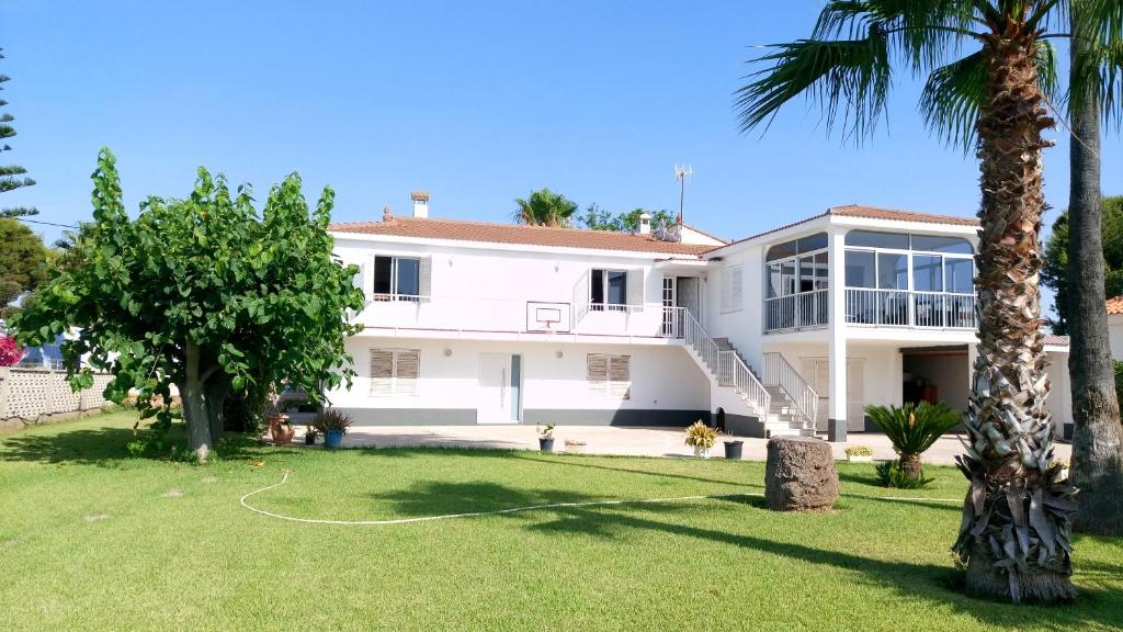 a white house with a yard with palm trees at Casa Cossis in Vinaròs