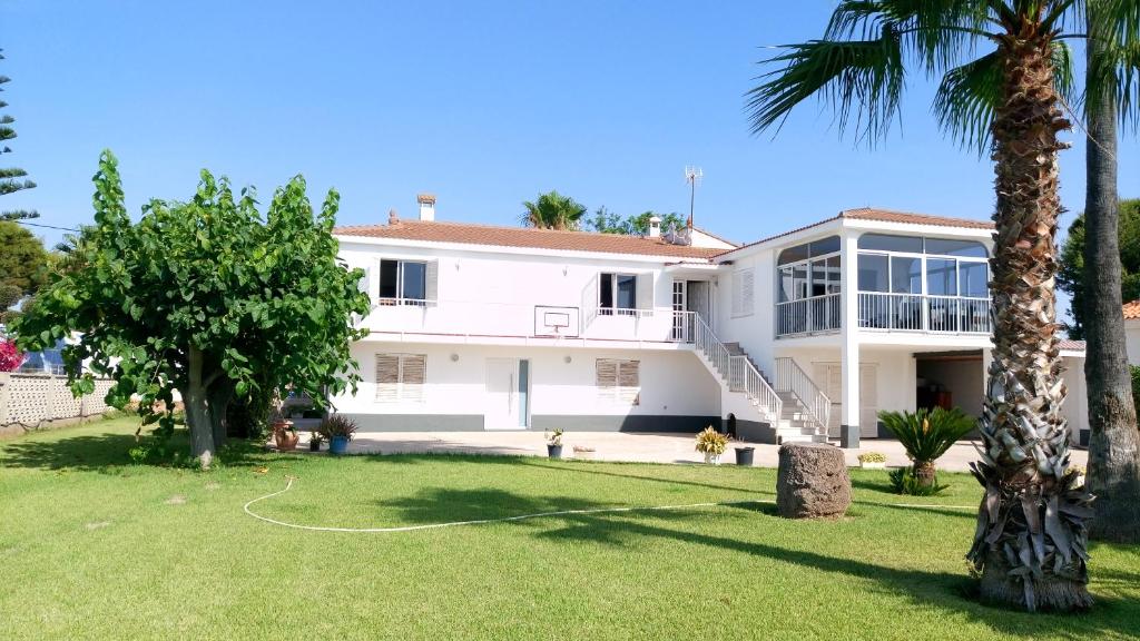 a white house with a yard with palm trees at Casa Cossis in Vinarós