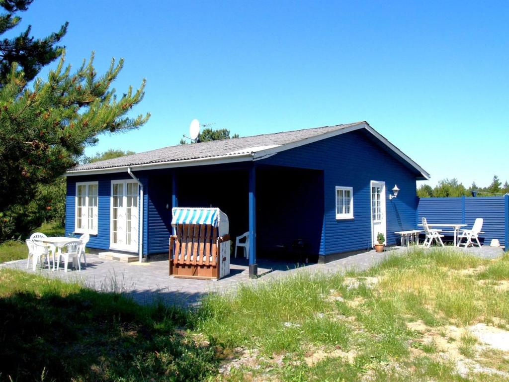 a blue house with two chairs and a patio at Holiday Home Redward - 1km from the sea by Interhome in Mølby