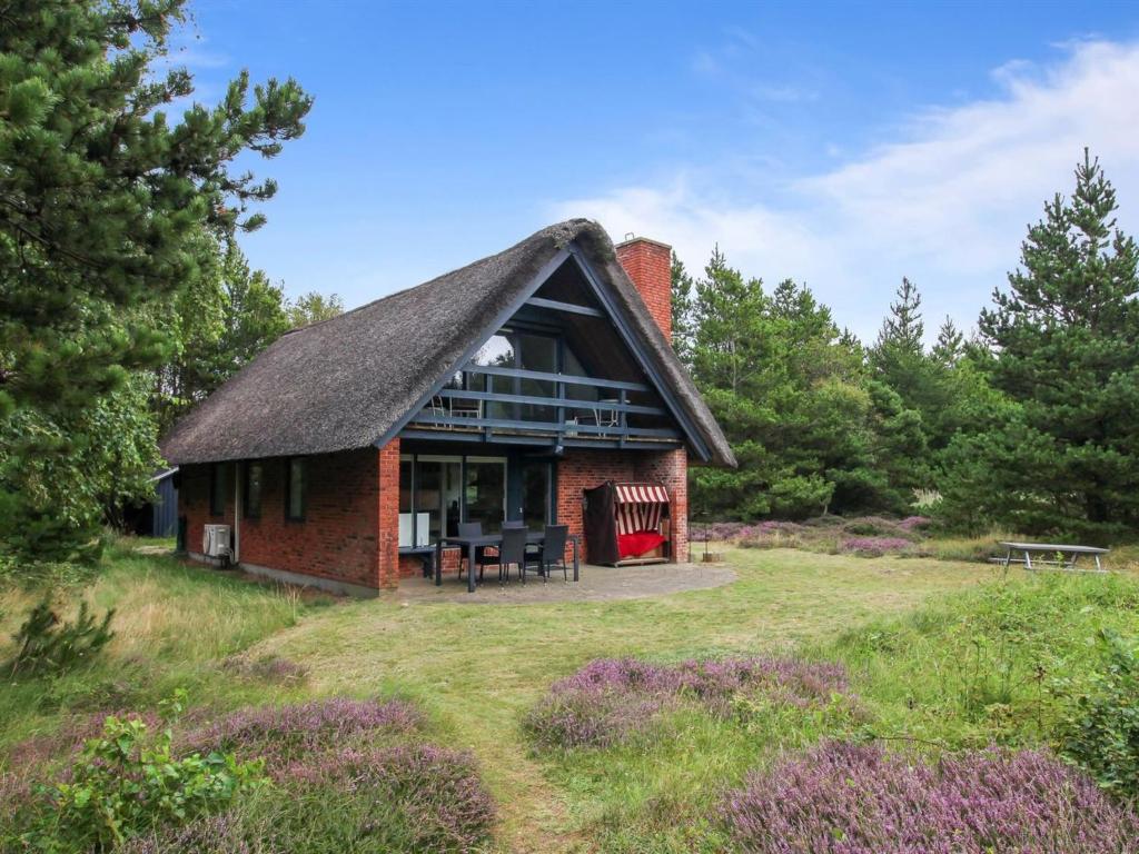 a small red brick house with a thatched roof at Holiday Home Anna - 1km from the sea by Interhome in Vesterhede
