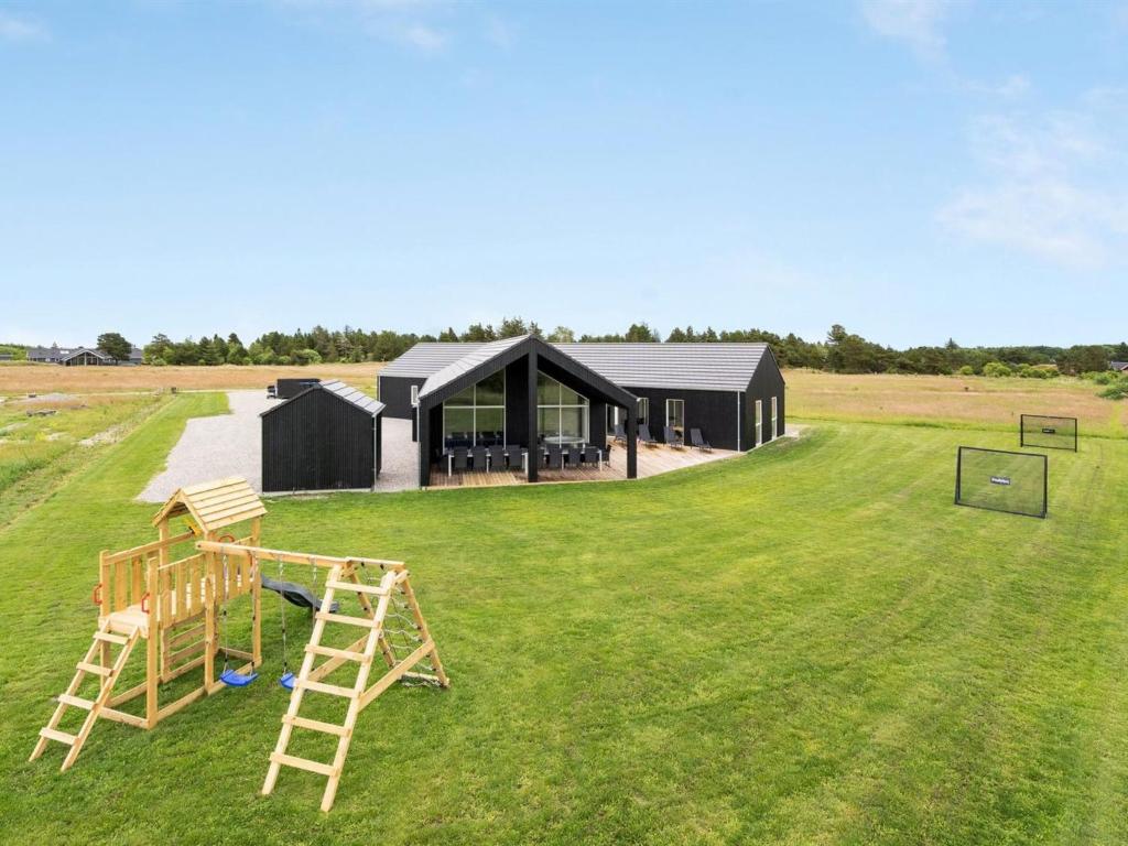 una casa nera con un parco giochi in mezzo a un campo di Holiday Home Fridel - 4km from the sea by Interhome a Tagholm