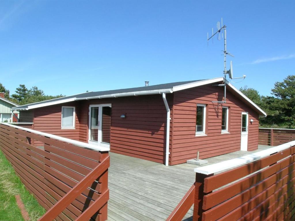 a house with a wooden deck next to a fence at Holiday Home Agir - 600m from the sea by Interhome in Vejers Strand