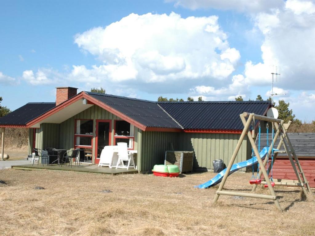 a small green house with a slide and a playground at Holiday Home Harmke - 1km from the sea by Interhome in Vejers Strand