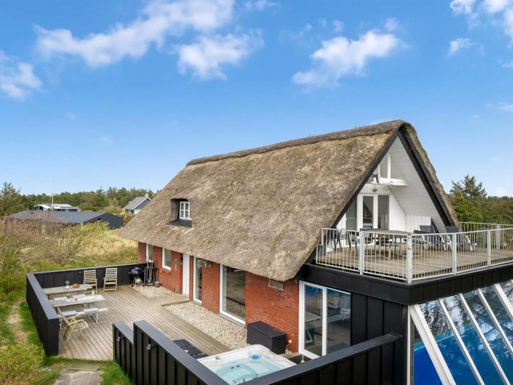a house with a thatched roof and a deck at Holiday Home Irlin - 800m from the sea by Interhome in Vejers Strand