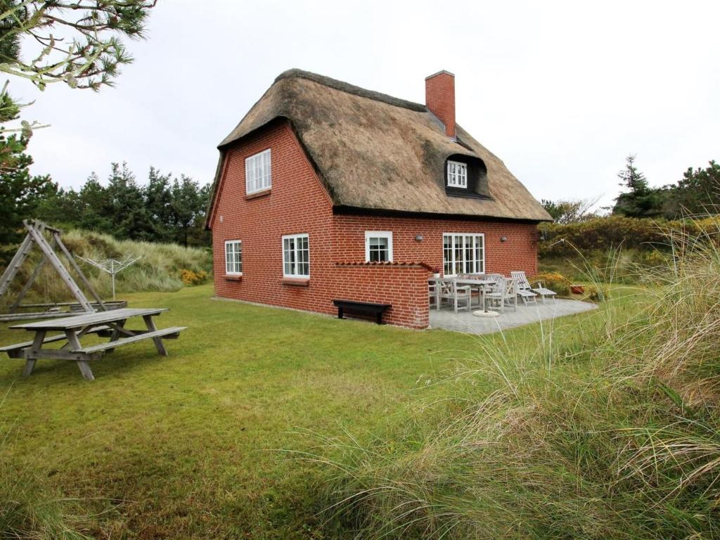 a red brick house with a table and a picnic table at Holiday Home Lioba - 400m from the sea by Interhome in Vejers Strand