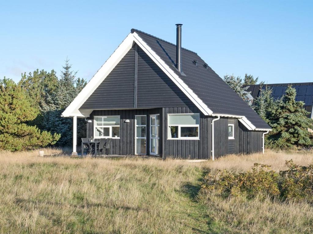 une maison noire sur une colline dans un champ dans l'établissement Holiday Home Tinemarie - 200m from the sea by Interhome, à Blåvand