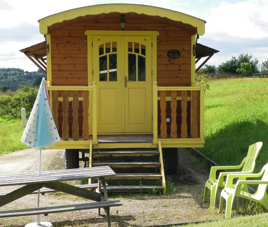 une petite cabine avec une porte jaune et une table de pique-nique dans l'établissement Les Roulottes des Korrigans, à Brasparts