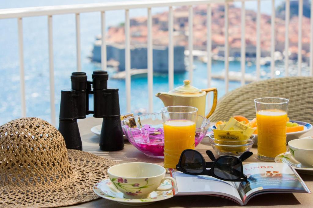 una mesa con un libro y vasos de zumo de naranja en Apartment Love and Hope en Dubrovnik