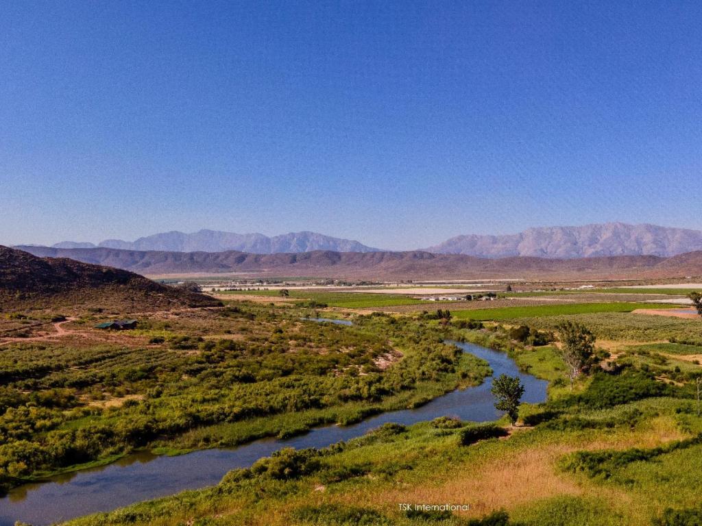 a river in a field with mountains in the background at Rivergrace Farm in Robertson