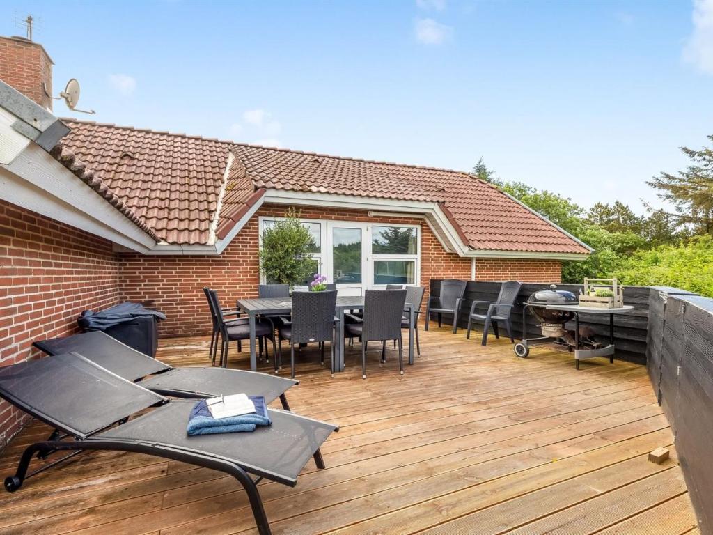 eine Holzterrasse mit Stühlen und Tischen auf einem Haus in der Unterkunft Holiday Home Sylvi - 1-7km from the sea by Interhome in Ringkøbing