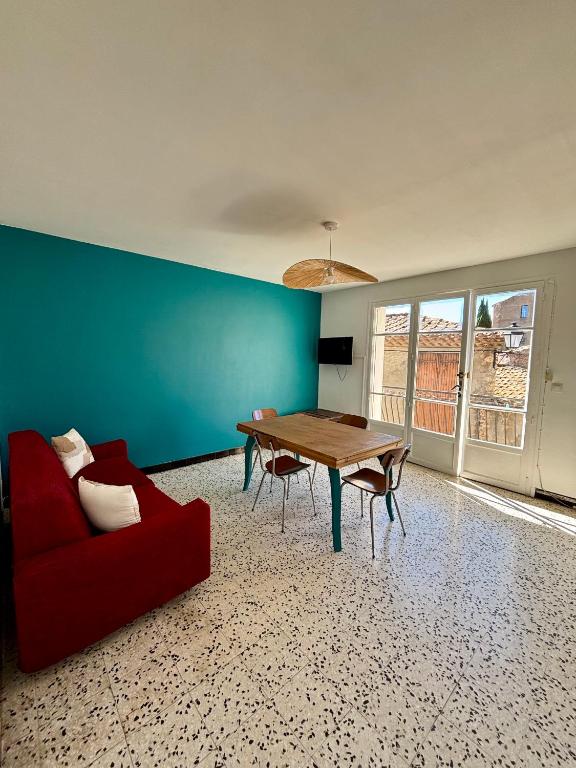 a living room with a table and a red couch at Chez Mamé Marie in Fraissé-des-Corbières