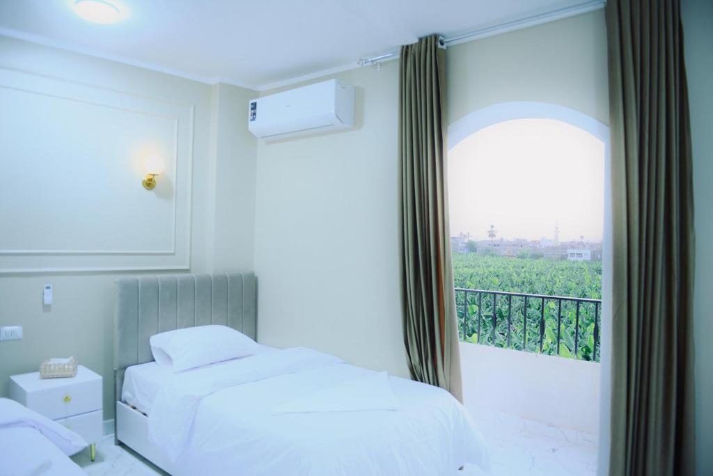 a bedroom with two beds and a window with a balcony at Paradise House Holiday in Luxor