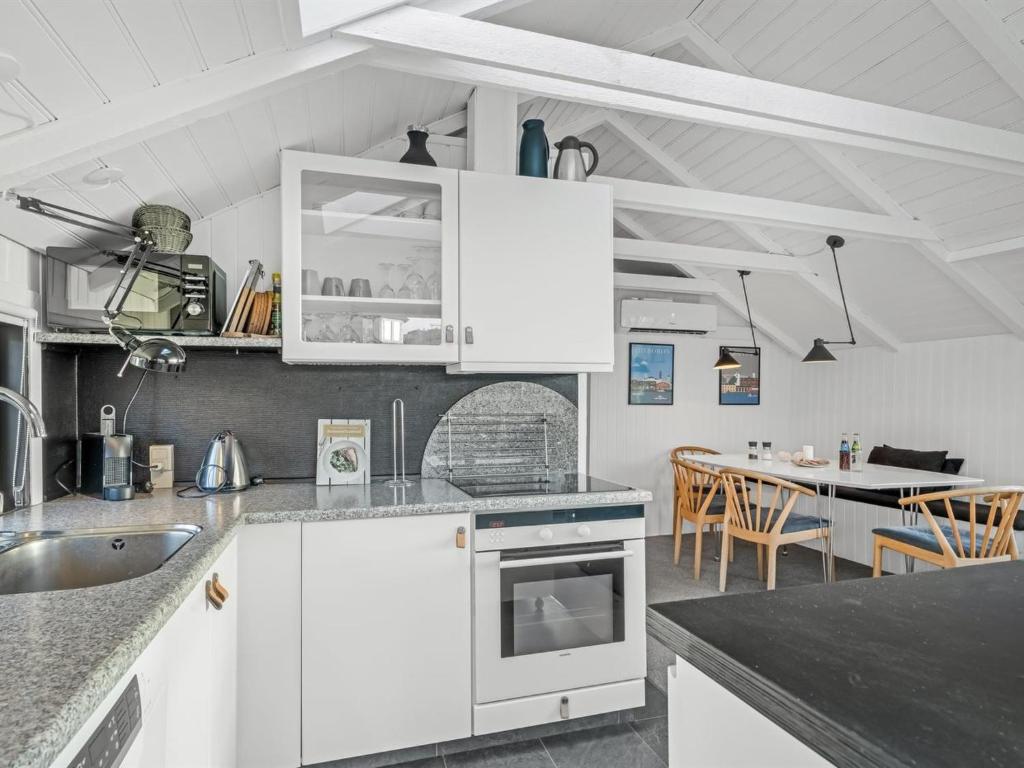 een keuken met witte kasten en een eetkamer bij Holiday Home Aksinja - 250m to the inlet by Interhome in Lemvig