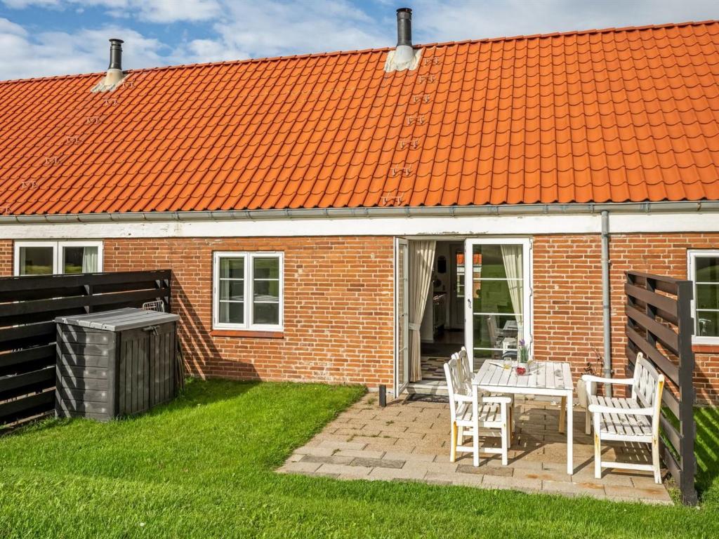 a brick house with an orange roof and a table and chairs at Apartment Smeralda - 200m from the sea by Interhome in Lemvig