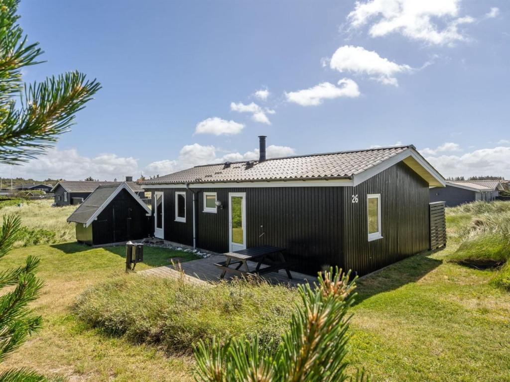 a small black house in the middle of a field at Holiday Home Usko - 250m from the sea by Interhome in Torsted