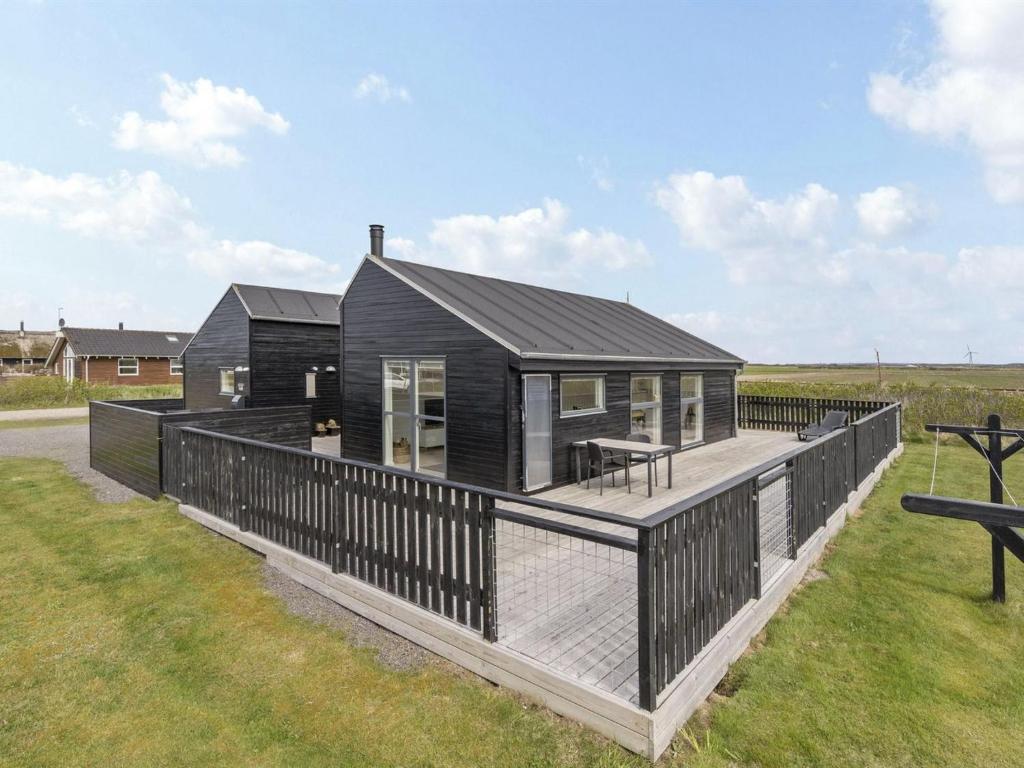 a black modular house with a deck at Holiday Home Damaskin - 300m from the sea by Interhome in Harboør