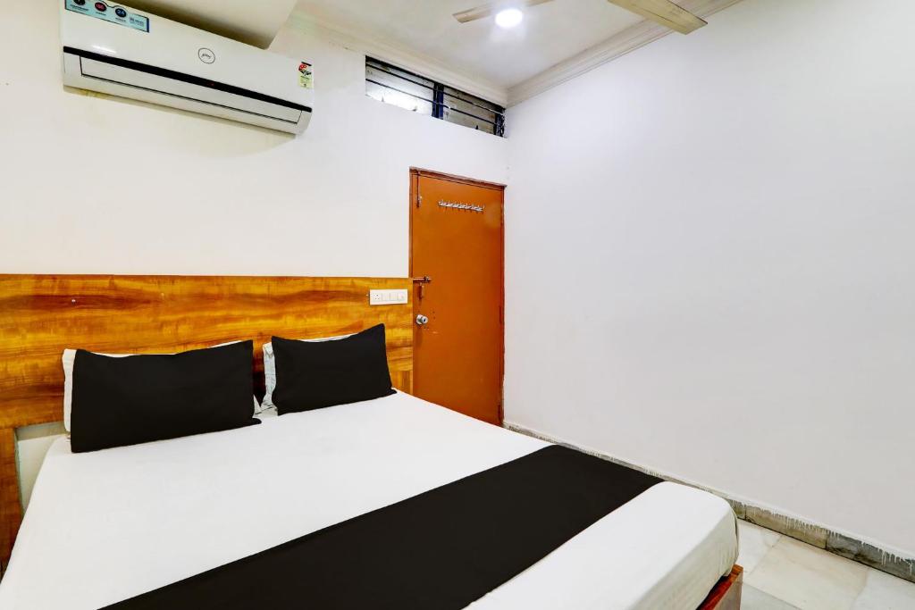 1 dormitorio con cama blanca y almohadas blancas y negras en Hotel O Hotel New Hitech Inn, en Hyderabad