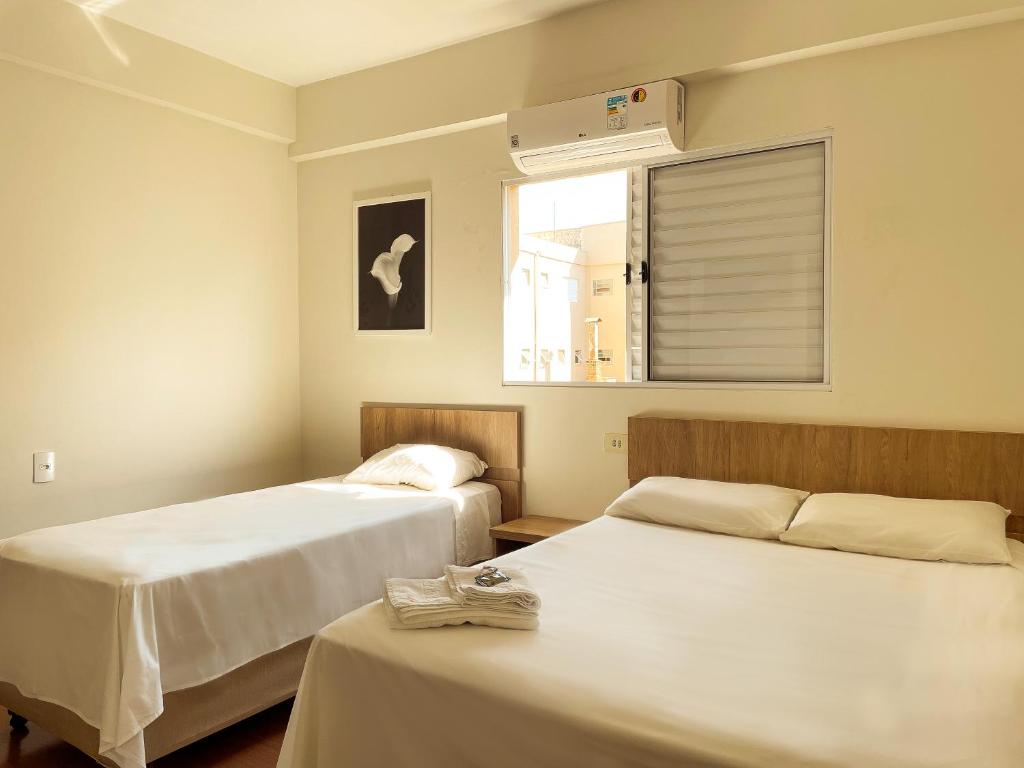 a room with two beds and a window with a fan at Lady Laura Hotel 