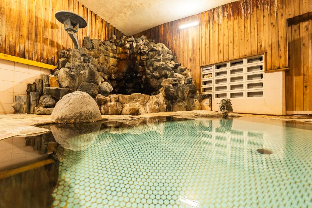 - une piscine avec une fontaine dans un bâtiment dans l'établissement Kaneki Hotel, à Yamanouchi
