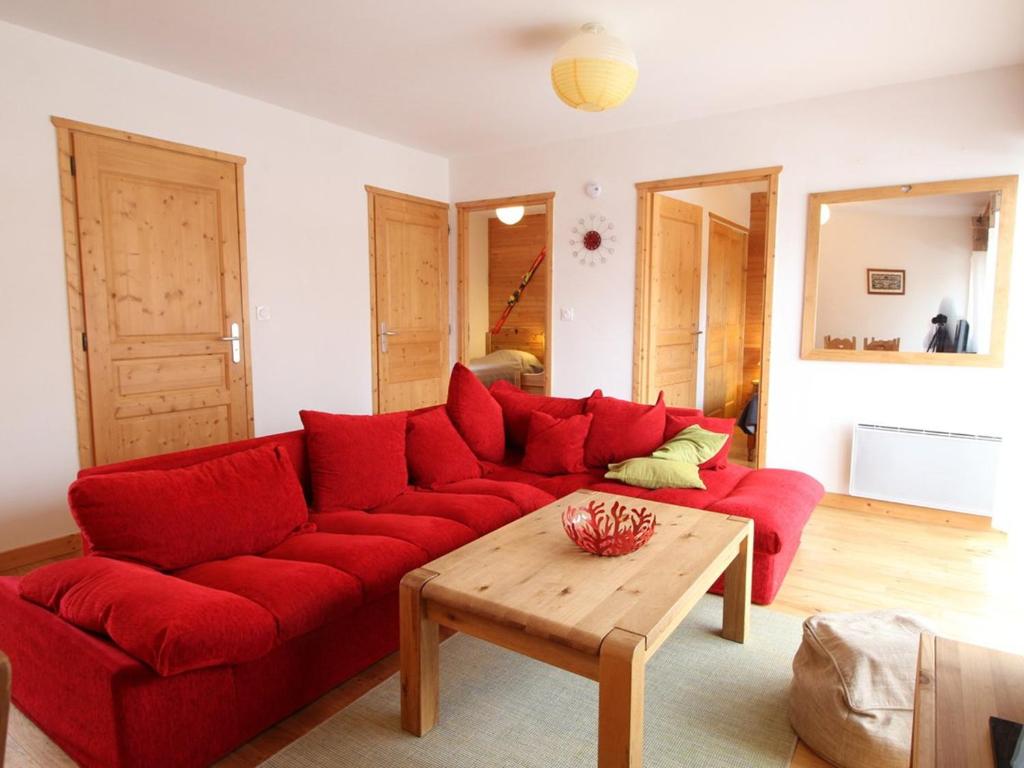 ein rotes Sofa im Wohnzimmer mit einem Holztisch in der Unterkunft 3 pièces cosy : Jardin, Wifi, Parking, 700m des pistes, 50m des commerces - FR-1-572-44 in Arâches-la-Frasse