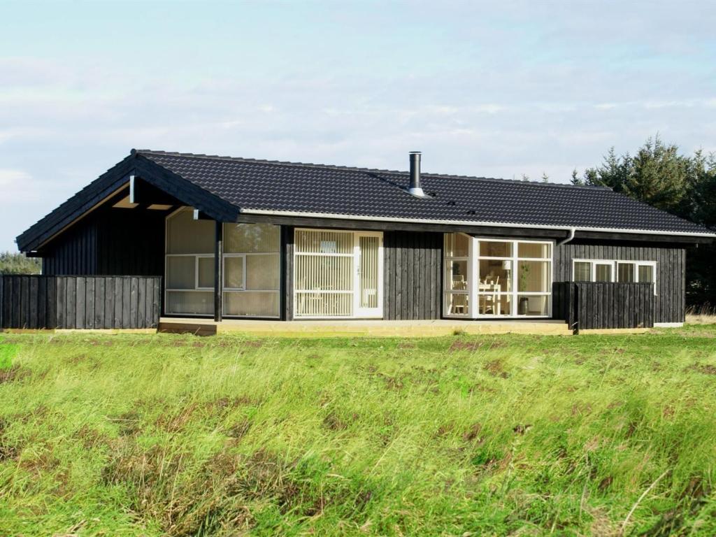 a house with a black roof and a grass field at Holiday Home Asol - 650m from the sea by Interhome in Løkken
