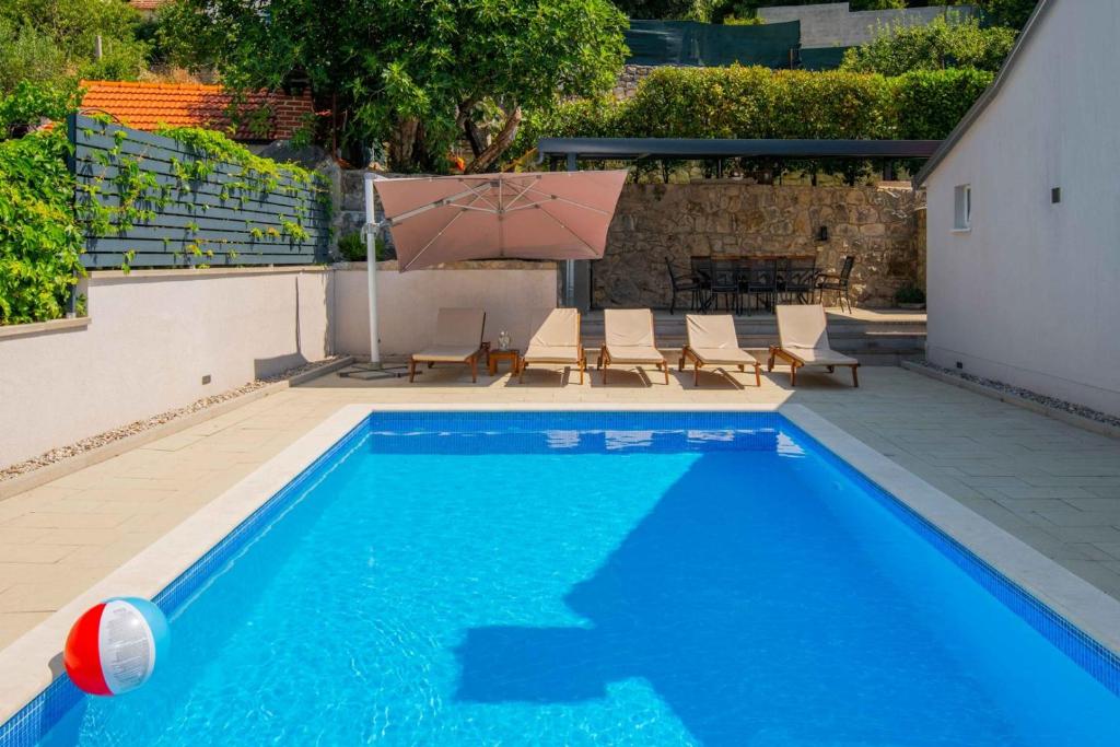 a blue swimming pool with chairs and an umbrella at Villa Velaria with private pool in Donja Glavina