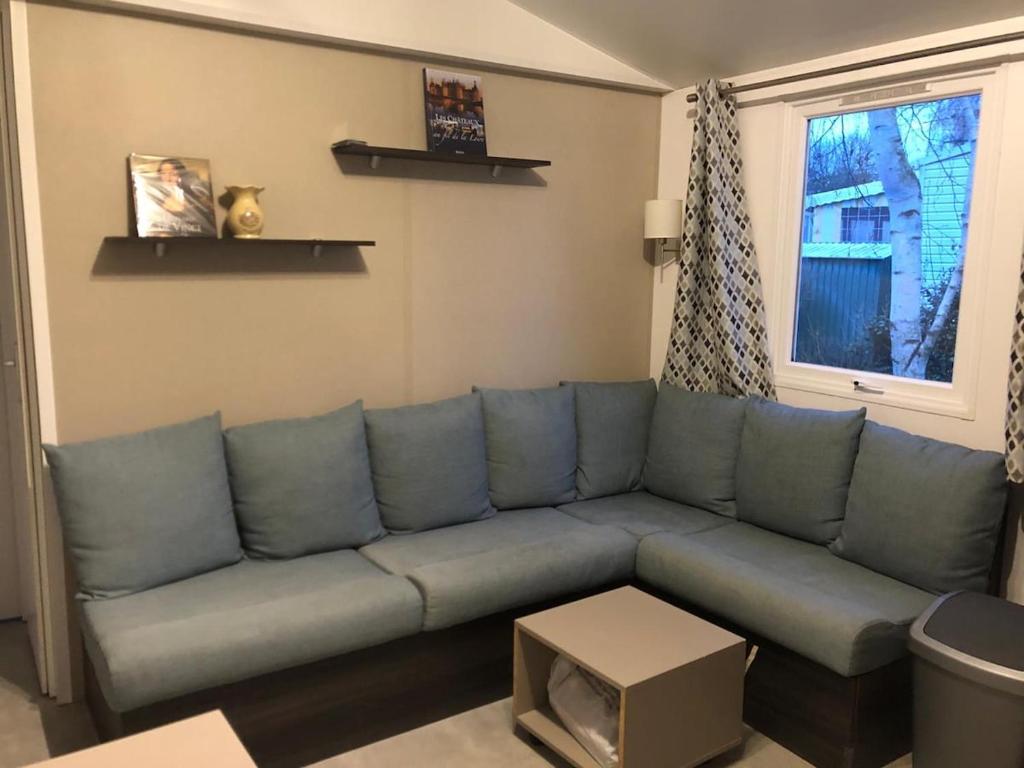 a blue couch in a living room with a window at Mobile home 2chs 4à5 pers 32m2 promo fun pass sept in Onzain